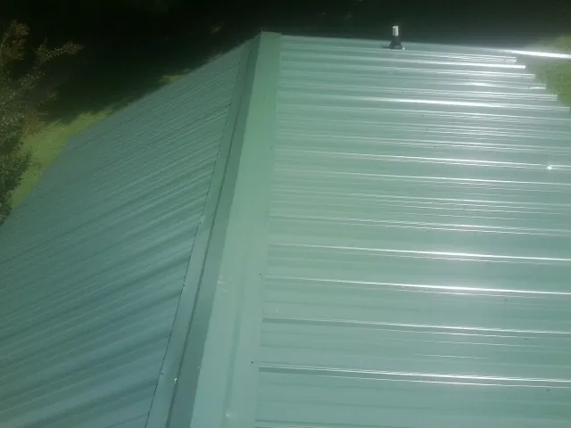 New green metal panels meeting at the ridge of a roof — Flat Roof Repair work by our crew in Nunn
