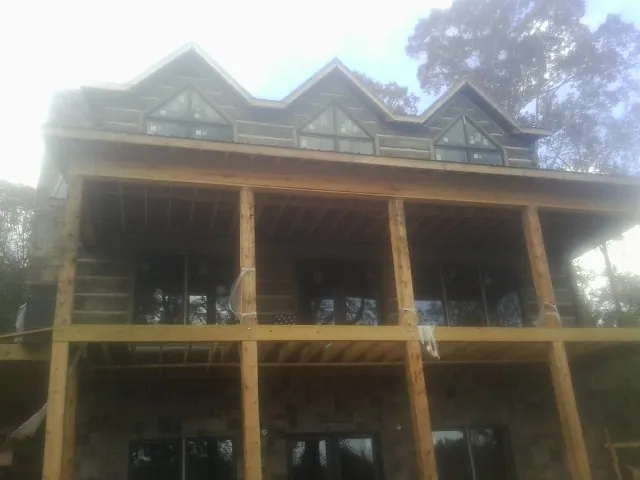 Dormers and porch framing on a large log home under construction — Roof Coating work by our crew in Nunn