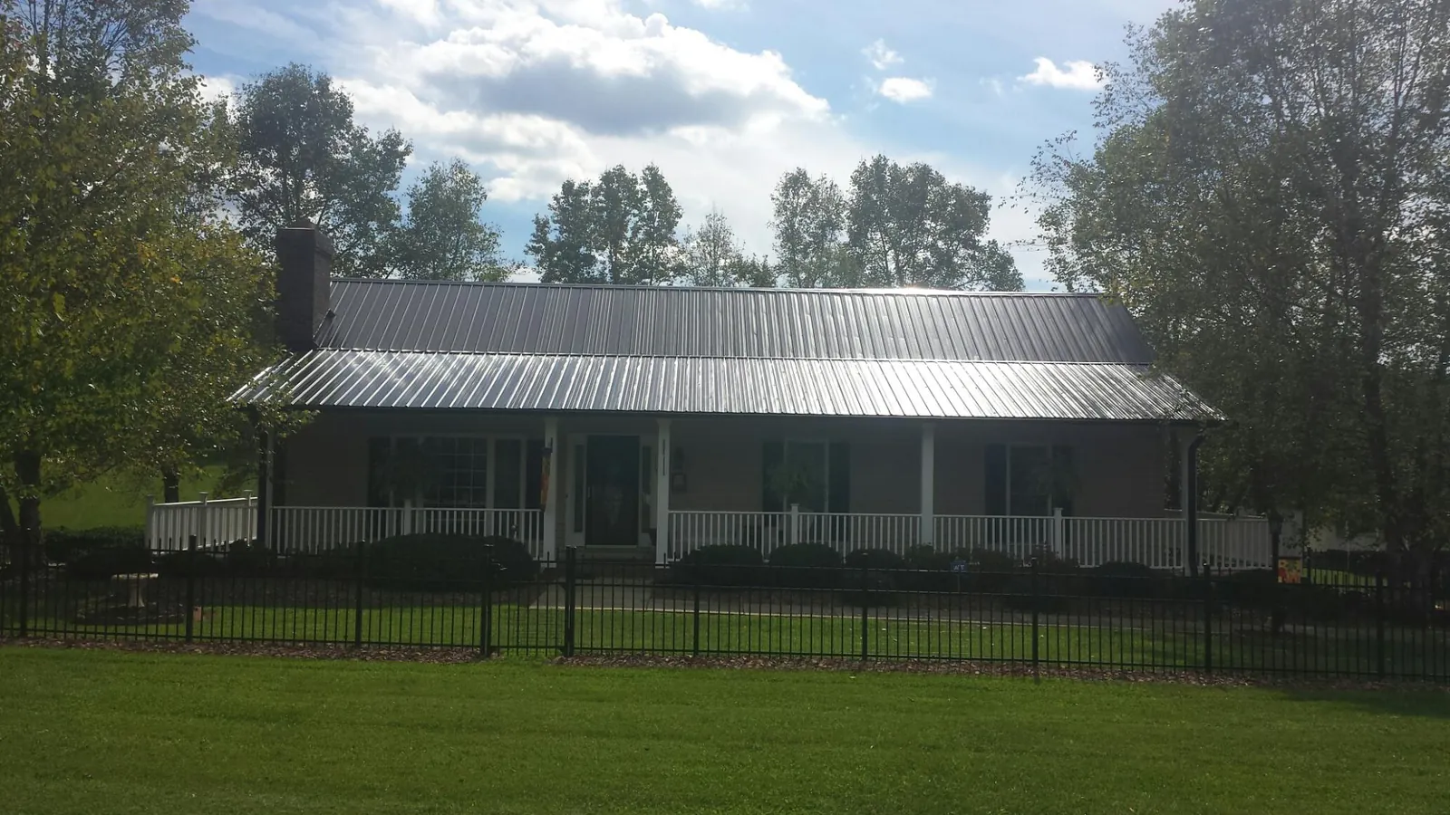 Gray metal roof on a brick ranch with a full width front porch — Gutter Guard Installation work by our crew in Nunn
