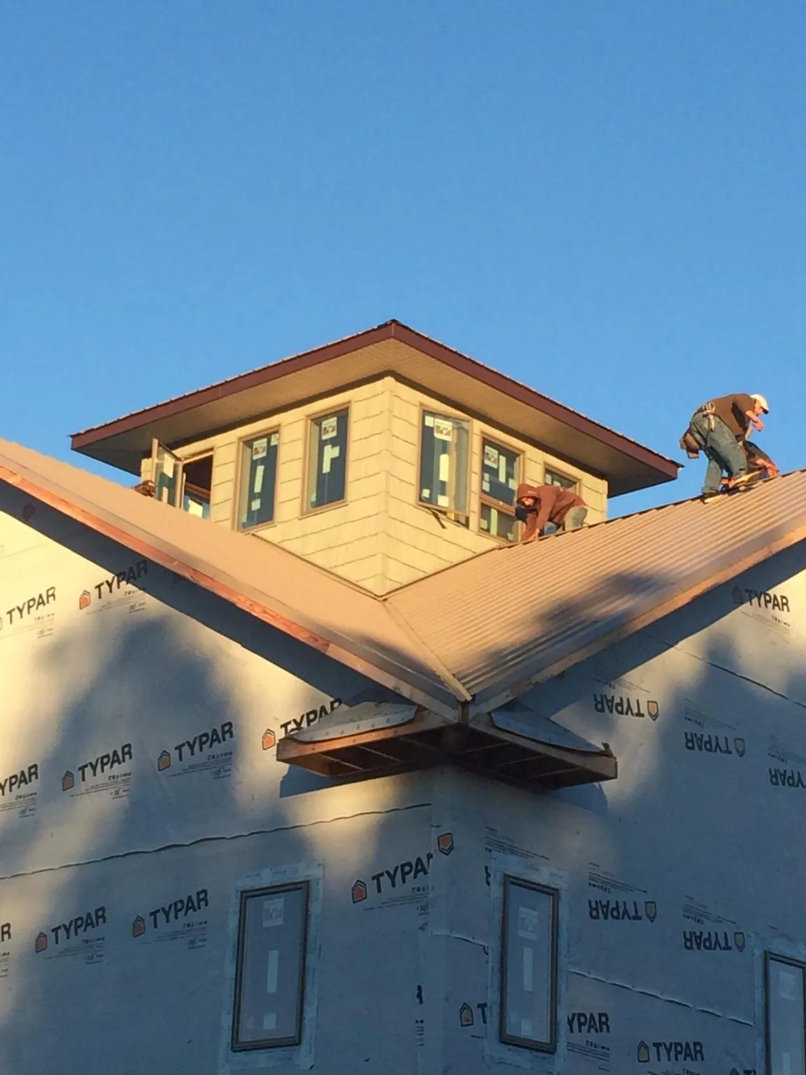 Roofers working around a rooftop cupola on a new metal roof at sunset — Roof Waterproofing in Nunn by Roofing Brothers